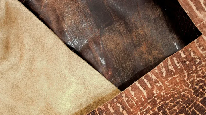 Tres recortes de cuero superpuestos: uno afelpado color arena, uno engrasado marrón oscuro con brillo y uno estampado en tonos rojizos