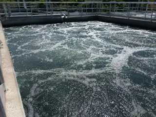 Piscina de aireación de la planta de tratamiento de aguas, con el agua en plena agitación y vetas de espuma blanca