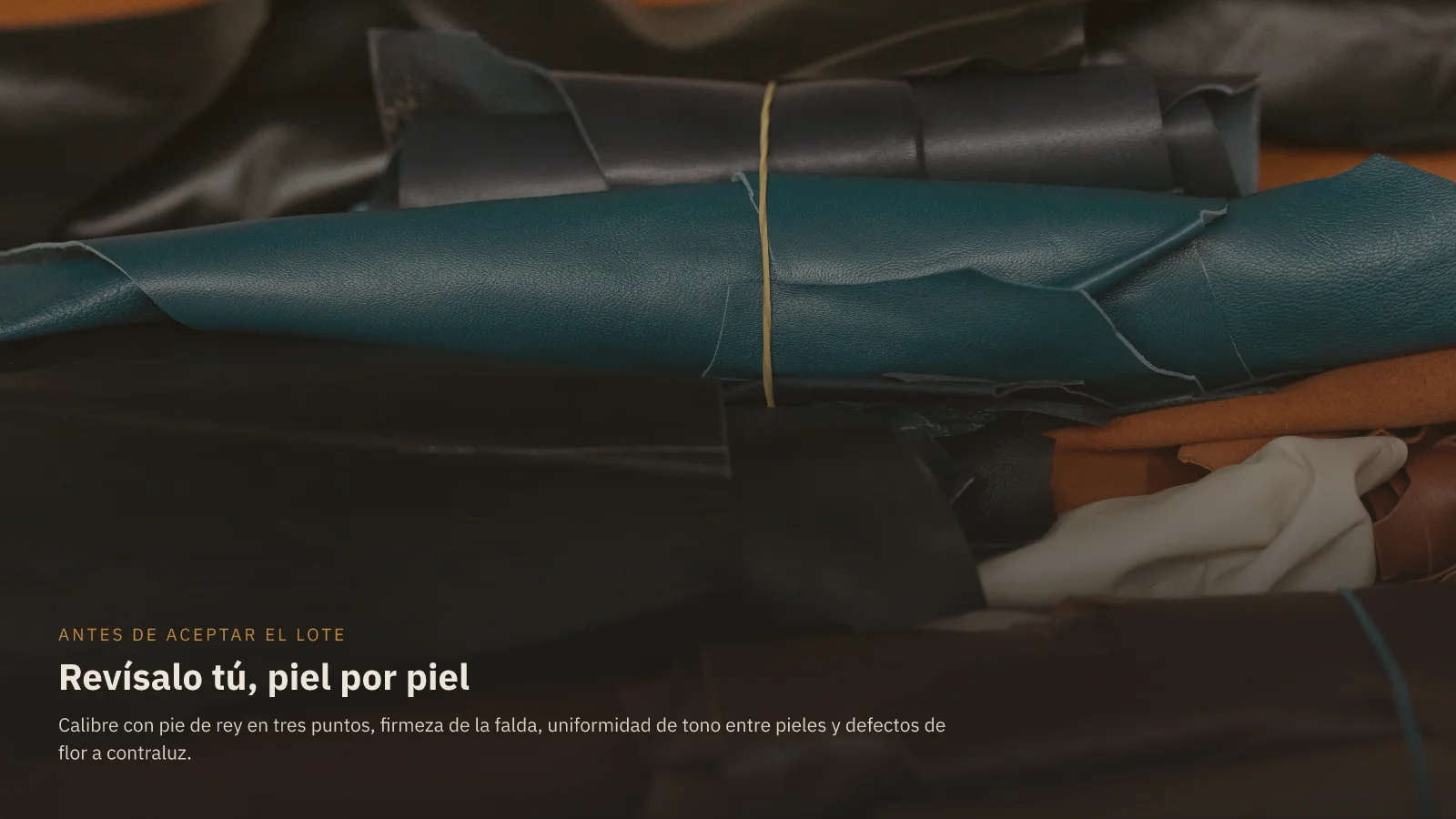 Pieles de cuero de varios colores enrolladas y apiladas sobre una mesa de revisión, con el rótulo Revísalo tú, piel por piel